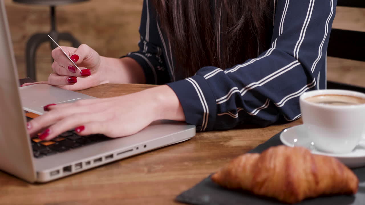 Woman using laptop with coffee and croissant