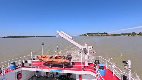 el barco viaja por el río con un cielo azul claro.