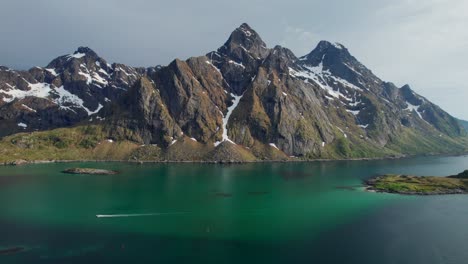 breathtaking aerial view of a boat sailing on the turquoise waters of the steinsfjorden, with the snow capped peaks of the lofoten islands in the background