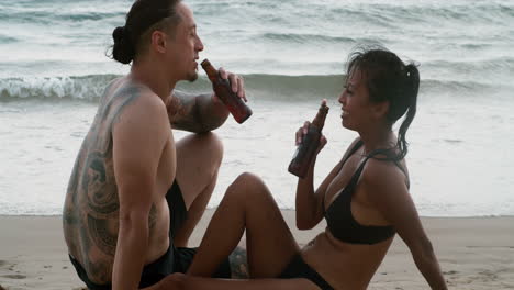 una pareja bebiendo cerveza en la playa.