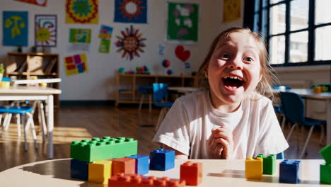 excited child playing with building blocks in classroom