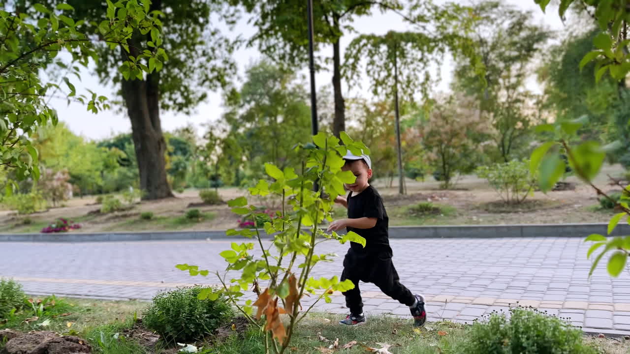 Active playful toddler jumping outdoors. Caucasian baby boy having good time in the park.