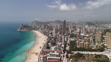 benidorm, spain: drone flies high and forward, offering a sweeping aerial over its famous beach and capturing the dense, modern skyline fronting the mediterranean coast.