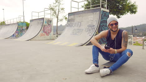 Young-boy-taking-a-selfie-in-a-skate-park-with-graffiti-on-background