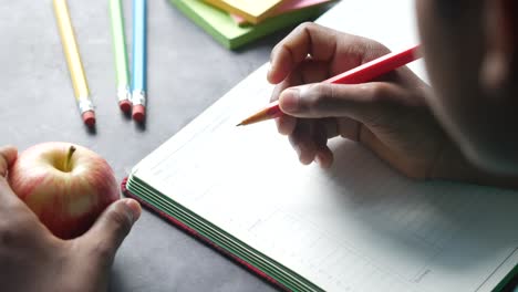 persona escribiendo en un planificador con una manzana