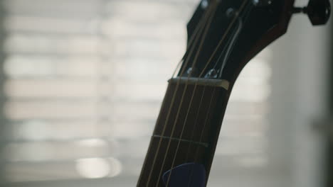 guitar neck and headstock with pick wedged in the strings