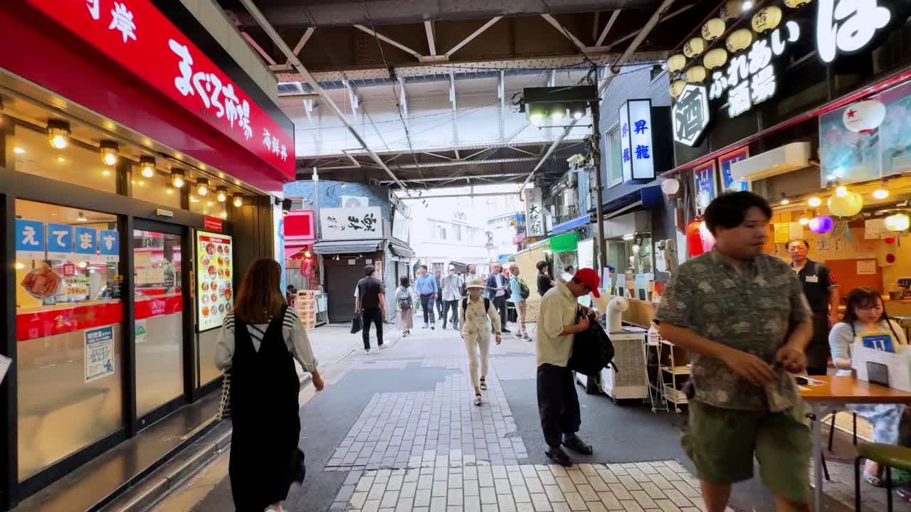 Bustling street market in Ueno Tokyo with colorful shops, food stalls, and people walking around