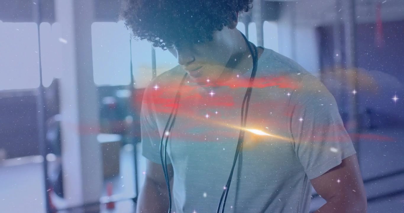 Male exerciser gripping jump rope testing tension in gym cosmic overlay signaling workout start