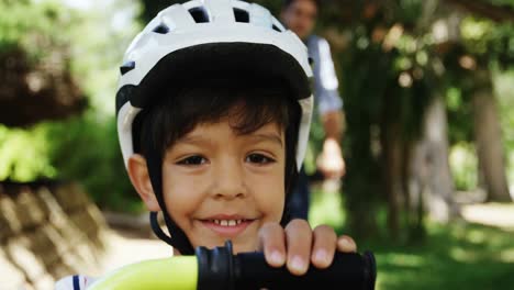 portrait of smiling boy wearing bicycle helmet in park