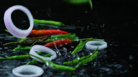 Freshly-chopped-green-chili-pepper,-and-sliced-onion-ring-falling-in-the-water