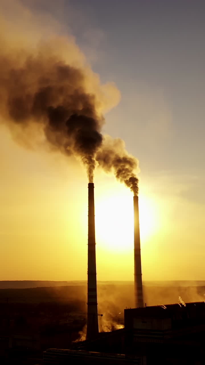 Aerial view over power plant. Aerial view of powerplant with smoke coming out of the chimneys Vertical video