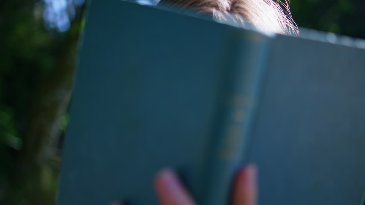 Girl reader looking camera in sunny summer forest closeup. Happy woman with book