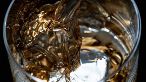 close-up of alcohol poured over a single ice cube