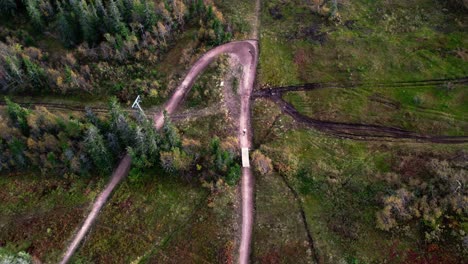 Aerial-shot-of-two-people-going-downhill-biking-in-Sälen,-Sweden-during-a-fall-day