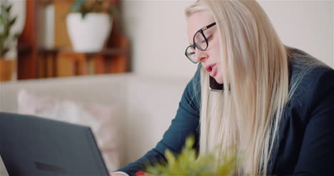 Geschäftsfrau,-Die-Am-Laptop-An-Einem-Projekt-Im-Homeoffice-Arbeitet,-Während-Sie-Mit-Dem-Kunden-Auf-Dem-Handy-Spricht-1