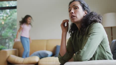 mixed race daughter jumping on the sofa, mother is stressed