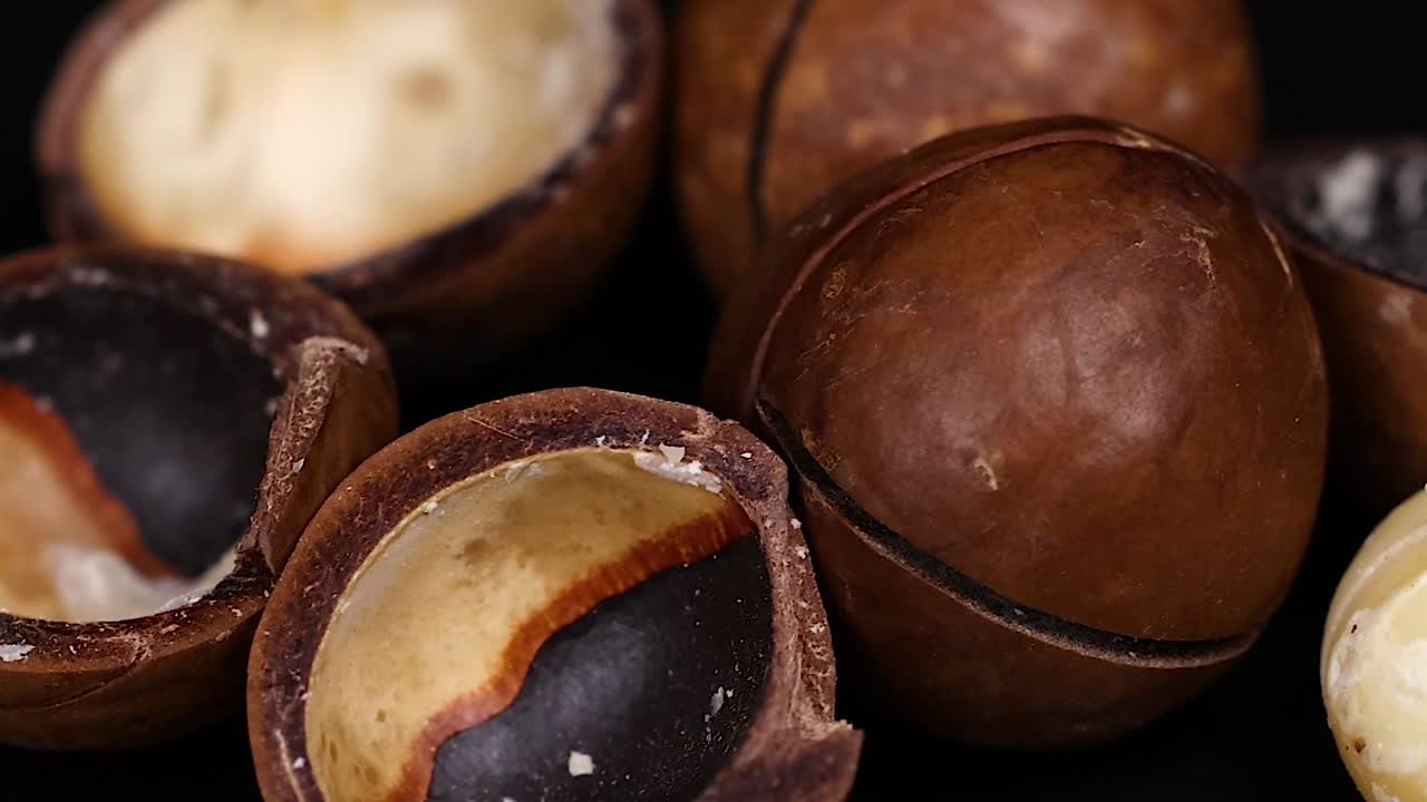 Vista dettagliata di gusci di noci di macadamia, che mostra la loro consistenza e la superficie lucida su uno sfondo scuro.