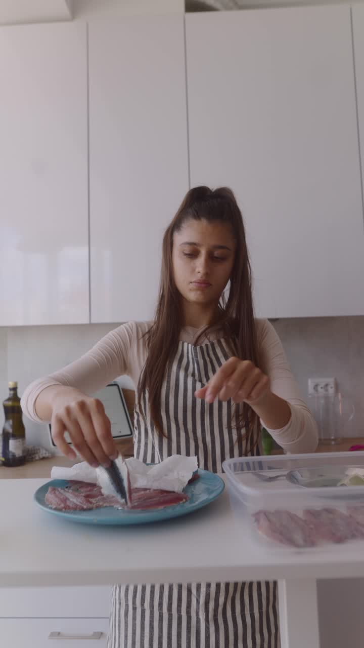 Woman preparing fish in kitchen