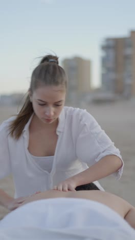 woman giving a back massage on the beach
