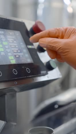 gloved hand operating an industrial control panel