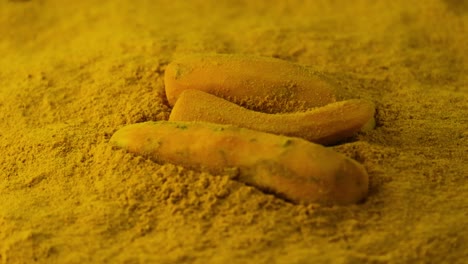 freshly peeled turmeric falling into the organic turmeric powder