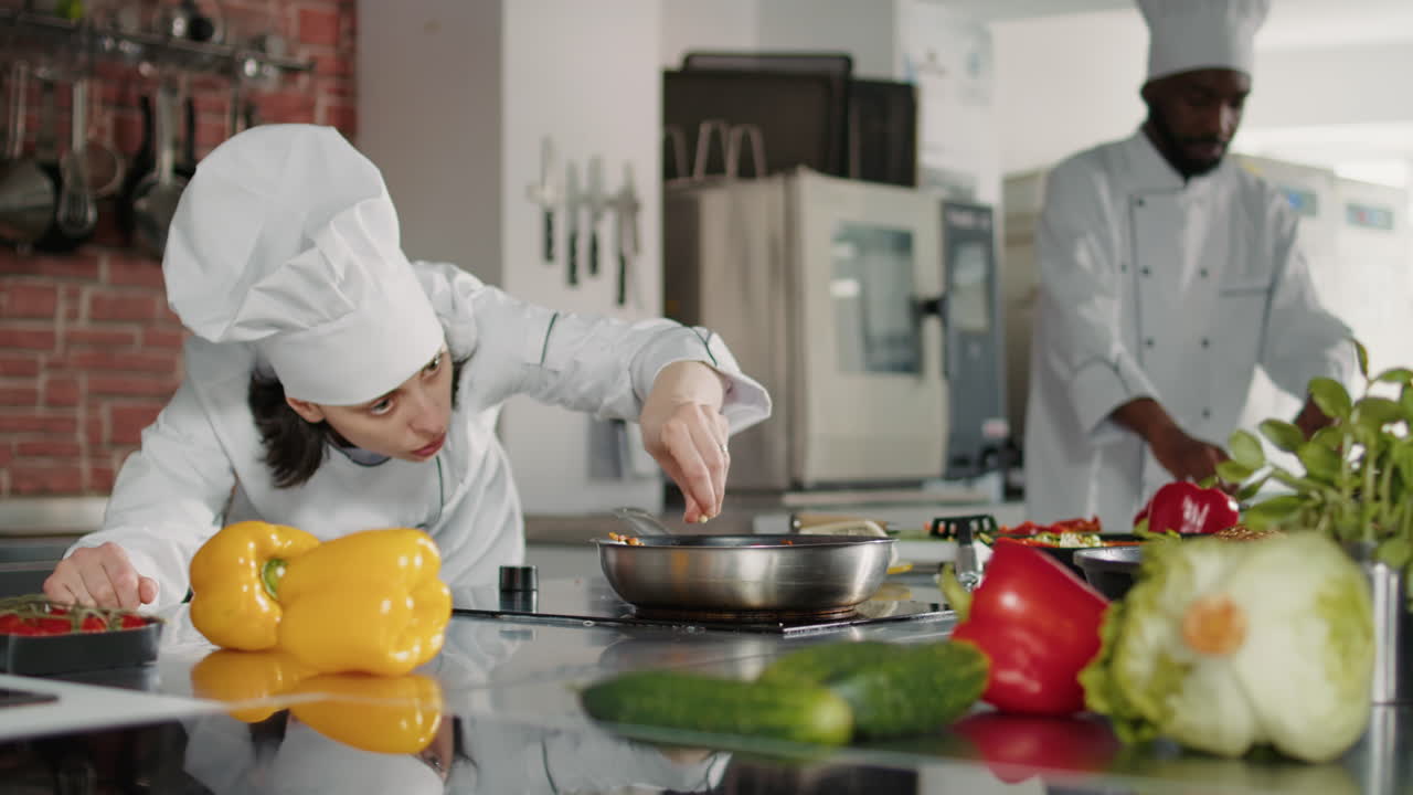 Female chef adding grated cheese on delicious food in pan