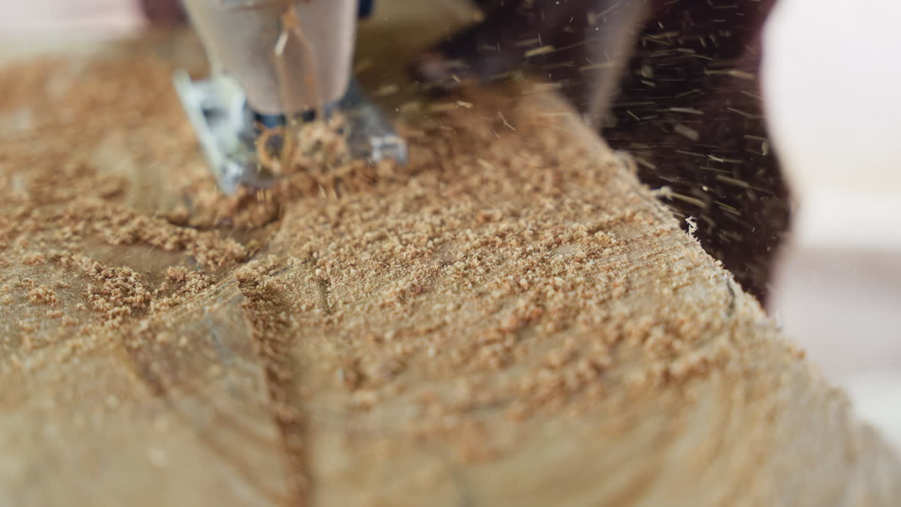 Closeup jigsaw cutting timber plank, fine sawdust spraying as blade carves groove, slow handheld motion, tight framing on wood texture, workshop craft atmosphere, artisan shaping furniture component