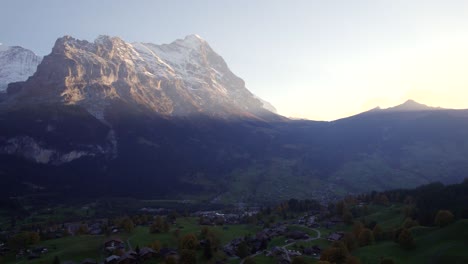imágenes aéreas de drones empujando sobre el pueblo de grindelwald y la cara norte del eiger bajo la impresionante luz del atardecer