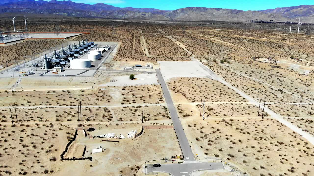 Power station, industrial complex in barren desert with wind turbines in distance, aerial 4k drone push, fly-in, in Palm Springs, Coachella Valley, Cabazon, California