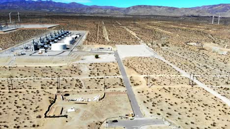 power station, industrial complex in barren desert with wind turbines in distance, aerial 4k drone push, fly-in, in palm springs, coachella valley, cabazon, california