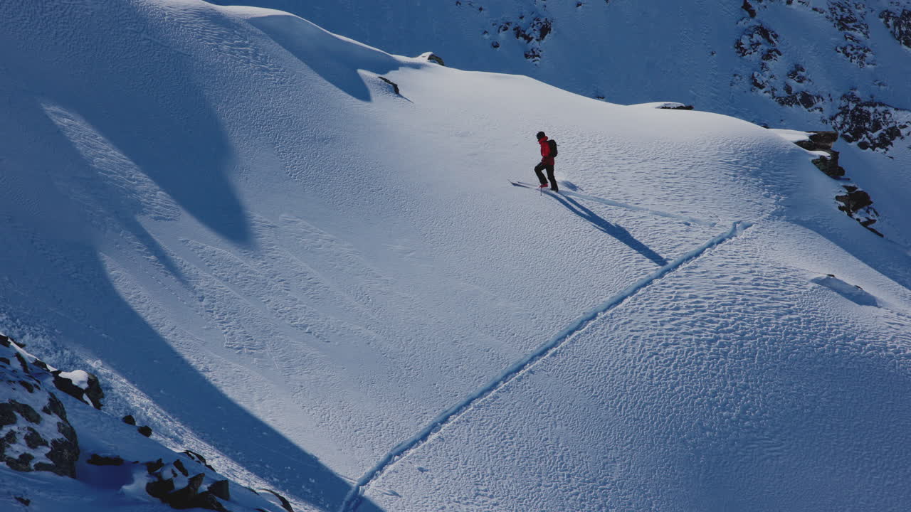 A professional skier hikes up a steep ridge in Verbier, then drops into an epic freeride descent. Pure adventure skiing in deep snow, dramatic terrain, and breathtaking alpine scenery.