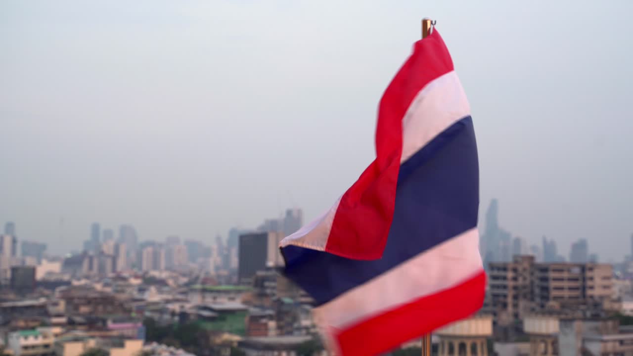 A Thai flag waving over the Bangkok skyline, symbolizing national pride with the cityscape in the background, establishing backdrop