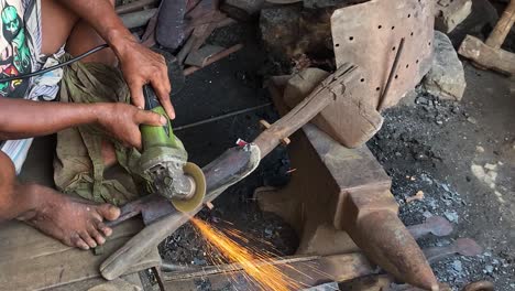 labourer using angle grinder on blade at workshop in dhaka, bangladesh