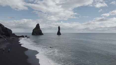 Aerial-View-Over-Black-Sand-Beach-Reynisfjara-With-View-Of-Reynisdrangar-Pillars-In-The-Background