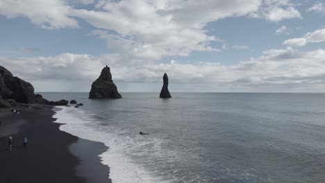 aerial view over black sand beach reynisfjara with view of reynisdrangar pillars in the background