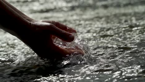 hands scooping water in current at a waterfall