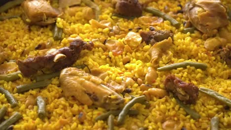 detailed close up of delicious colorful paella with meat, vegetables and rice in a huge pan