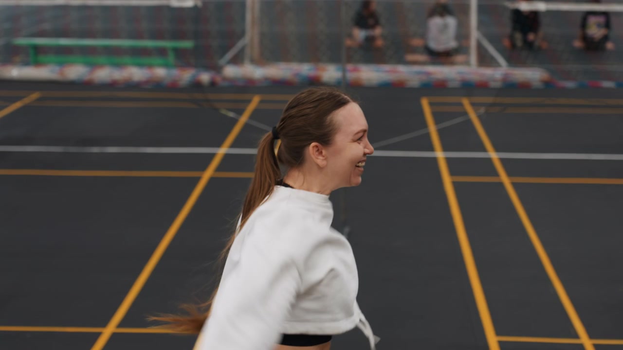Players enjoy upbeat badminton match together. Cheerful woman celebrates point in lively indoor game. Teammates share joyful moments and positive energy during competitive badminton match