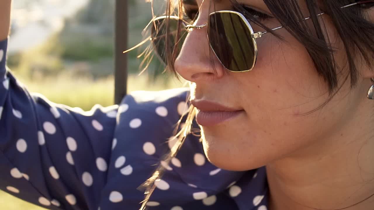 primer plano de una modelo con gafas de sol con el pelo ondeando al viento