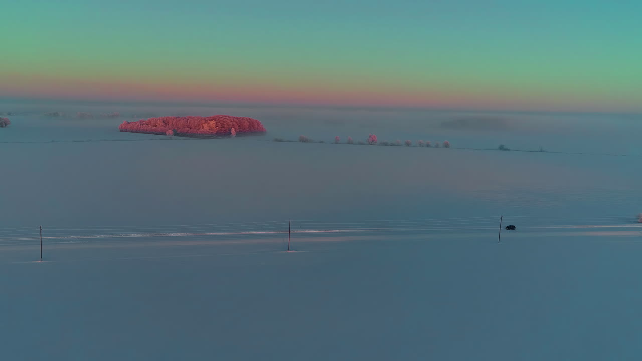 광활한 얼어붙은 풍경 속 눈 덮인 도로를 따라 운전하는 외로운 차량 - 조감도