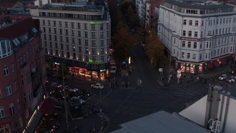 Tilt-down-reveal-of-traffic-on-Rosenthaler-Platz.-Busy-street-intersection-in-evening.-Berlin,-Germany