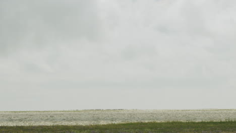 Handheld-slow-motion-shot-of-kite-surfer-surfing-in-the-north-sea