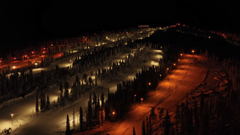 ascending drone shot in front of illuminated slopes of iso-syote, winter night in finland