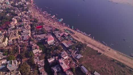 river port with buildings and parked vehicles at varanasi, banaras, kashi, uttar pradesh, india. day time, tilt down, drone shot, 4k.