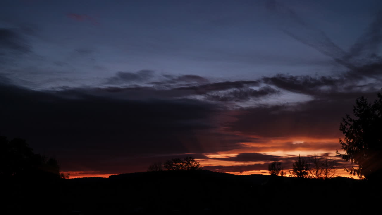 Timelapse van snel bewegende donkere wolken en warme lichtstralen die doorbreken.