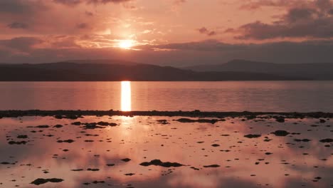 hermosa puesta de sol sobre el mar reflejada en el agua como un espejo y la arena húmeda