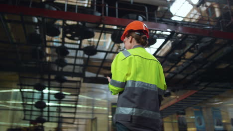 Woman-supervisor-holding-tablet-computer-at-huge-modern-manufacturing-storage.