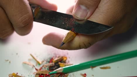 Footage-of-hands-slowly-sharpening-a-pencil-and-some-coloured-pencils-with-a-sharp-knife