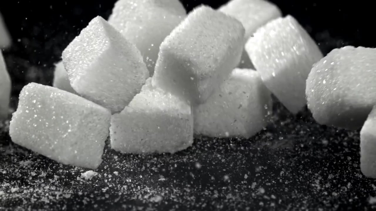 Terrones de azúcar blancos cayendo en cámara lenta sobre fondo negro