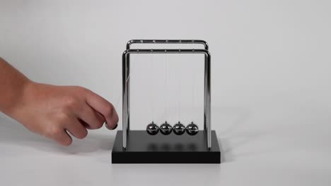 hand initiates motion of newton's cradle